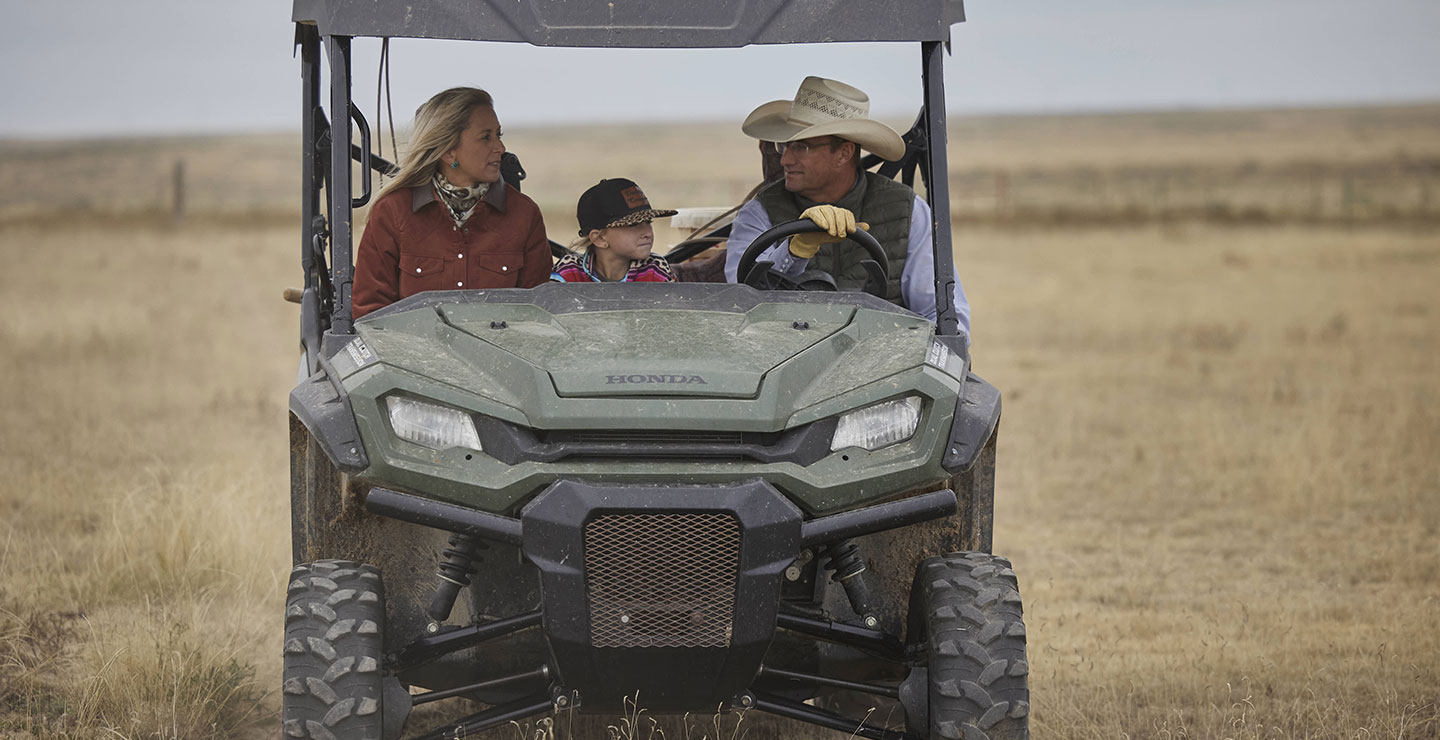 Una familia viajando en un vehículo todo terreno en el pasto mirando a su alrededor.